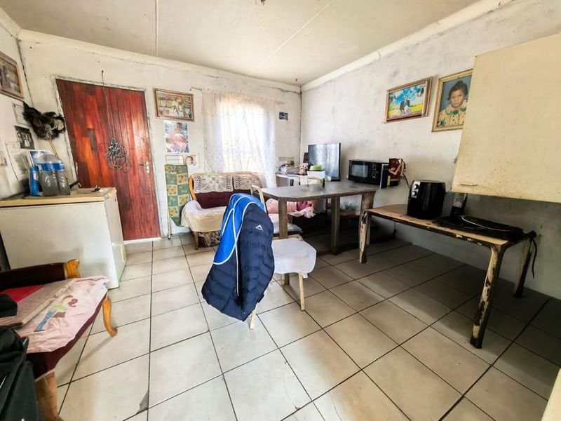 A living area featuring ceramic floor tiles and a timber entrance door, requiring cosmetic updates to the wall finishes and general maintenance.