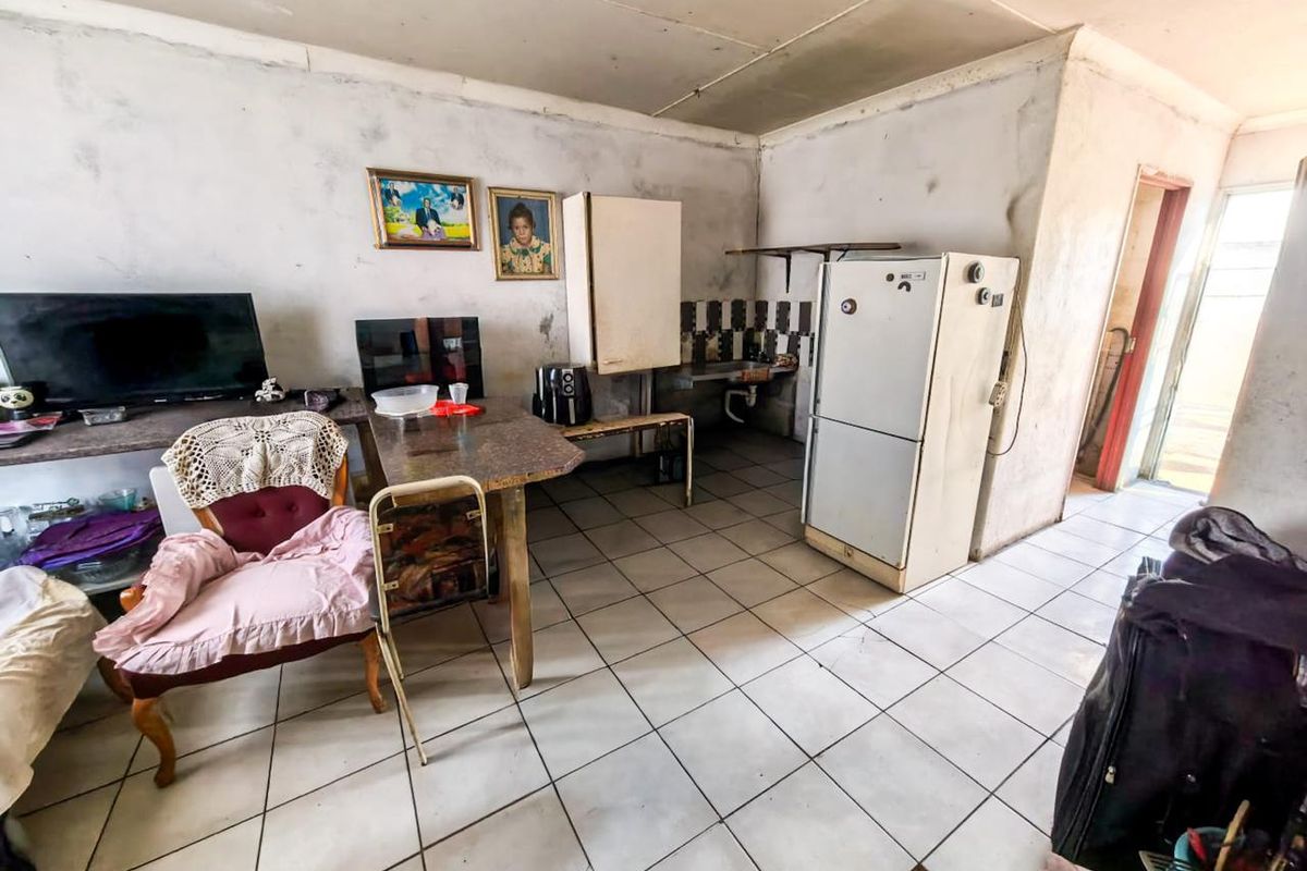 A dated kitchen area featuring tiled flooring and splashbacks, requiring significant renovation and cosmetic updates to improve the overall condition and functionality.