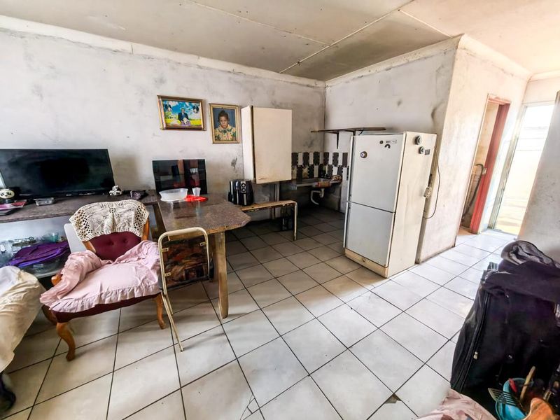 A dated kitchen area featuring tiled flooring and splashbacks, requiring significant renovation and cosmetic updates to improve the overall condition and functionality.
