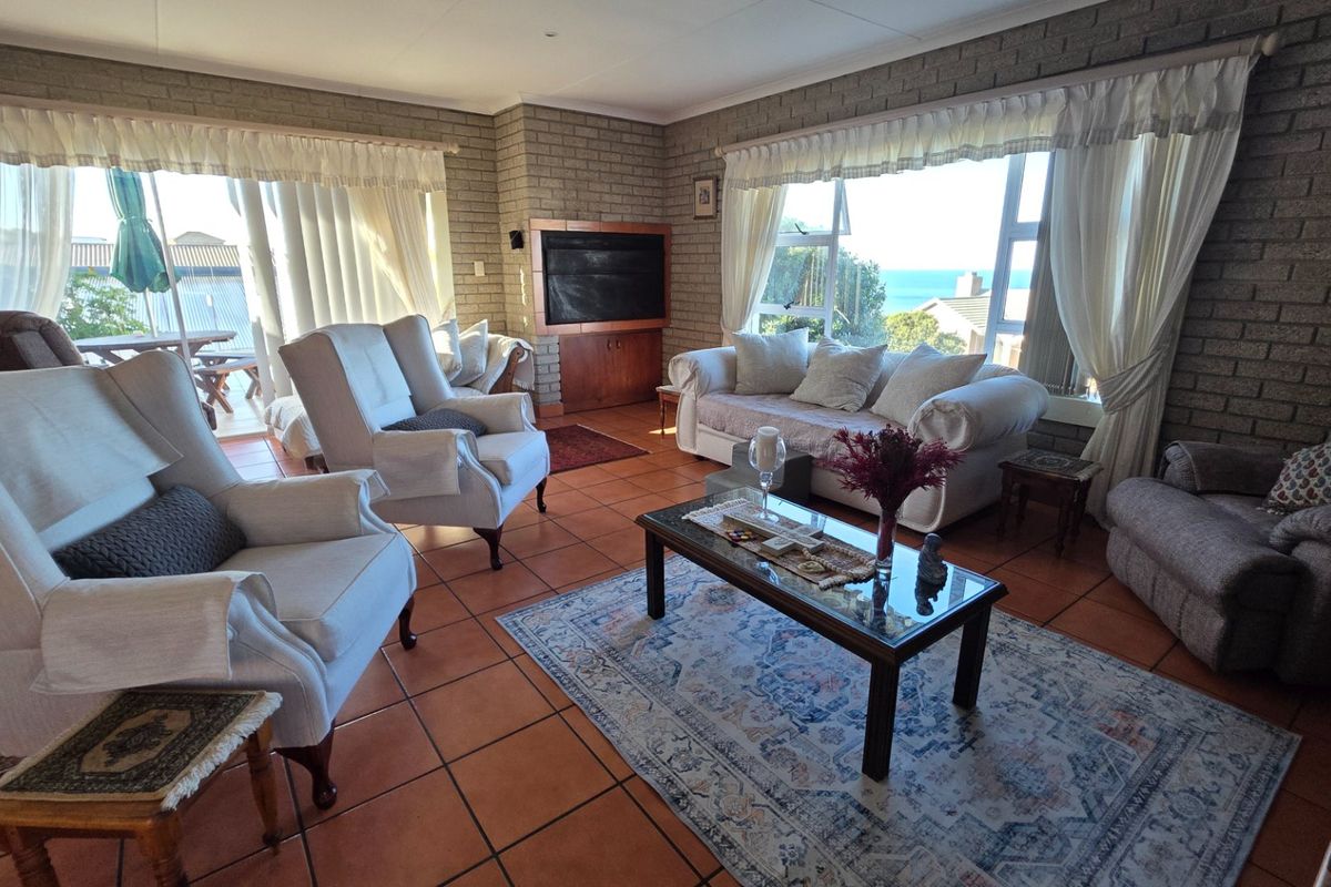 Spacious living room featuring exposed brick walls, terracotta floor tiles, and large windows with natural light and ocean views.