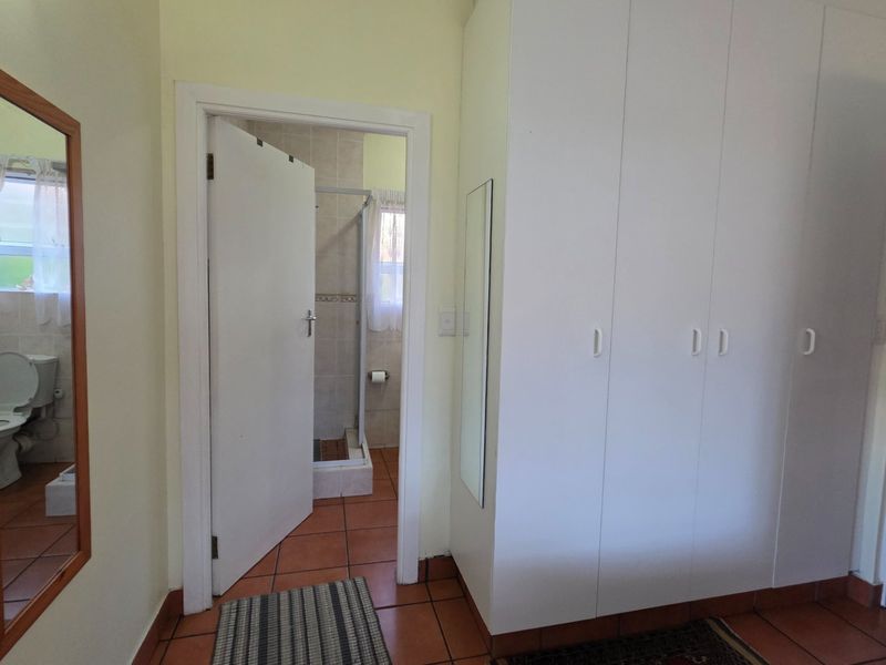 Bedroom featuring built-in cupboards, tiled flooring, and direct access to an en-suite bathroom.