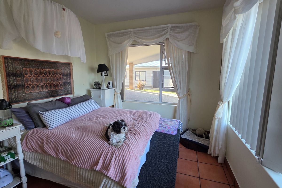 A bedroom featuring tiled flooring and large windows that provide natural light and views of the exterior property.