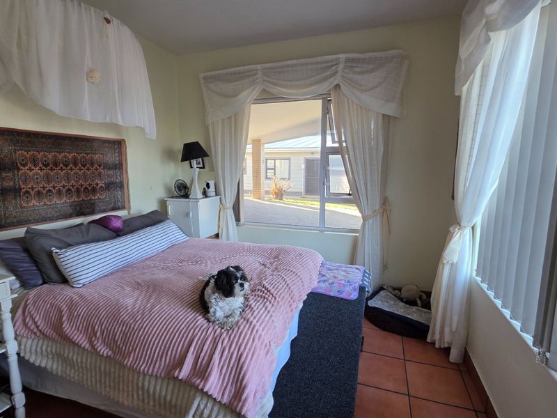 A bedroom featuring tiled flooring and large windows that provide natural light and views of the exterior property.