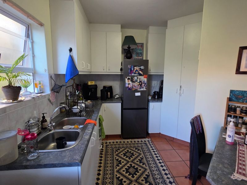 A functional kitchen featuring white cabinetry, laminate countertops, a double bowl sink, and tiled flooring, offering a practical layout for daily use.