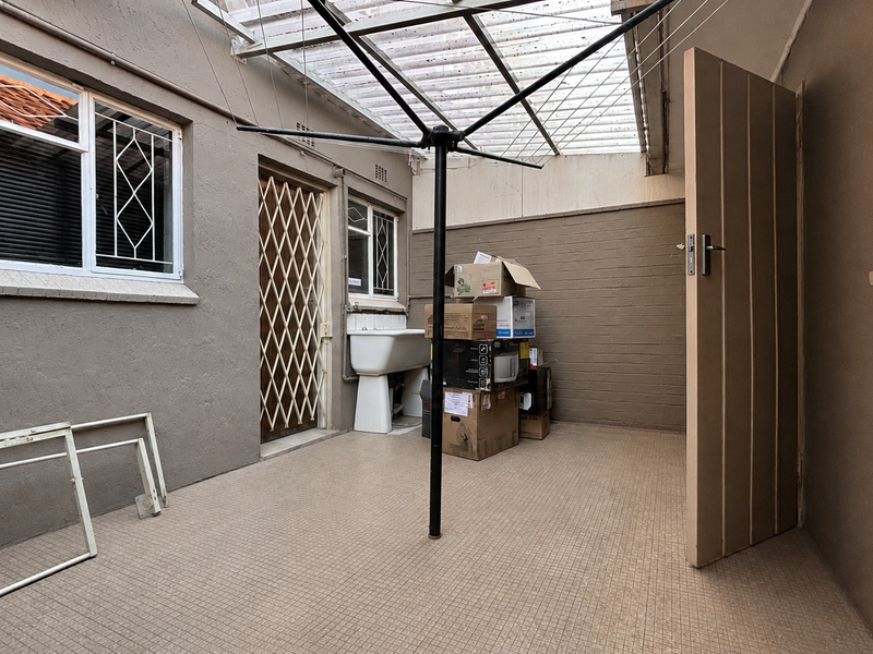 A functional outdoor laundry area featuring a utility sink, tiled flooring, and a covered roof structure, providing a practical space for household chores.