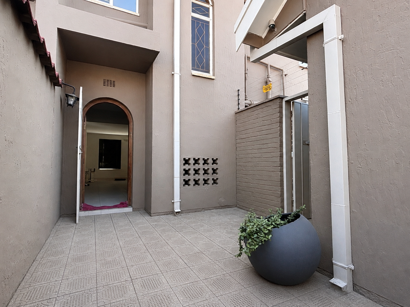 A private rear courtyard featuring tiled flooring, an arched entrance, and functional exterior architectural details.