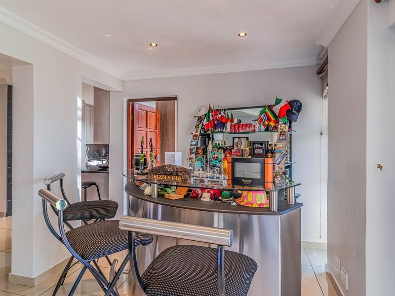 A dedicated bar area featuring a modern built-in counter, recessed lighting, and tiled flooring, seamlessly integrated into the home's living space.