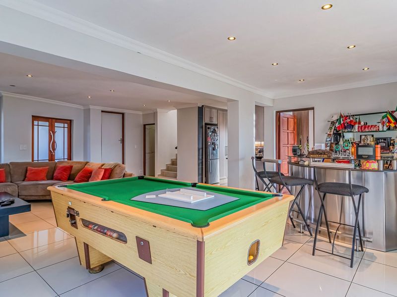 Spacious open-plan living area featuring tiled flooring, recessed lighting, and a built-in bar, providing a versatile space for entertainment and relaxation.