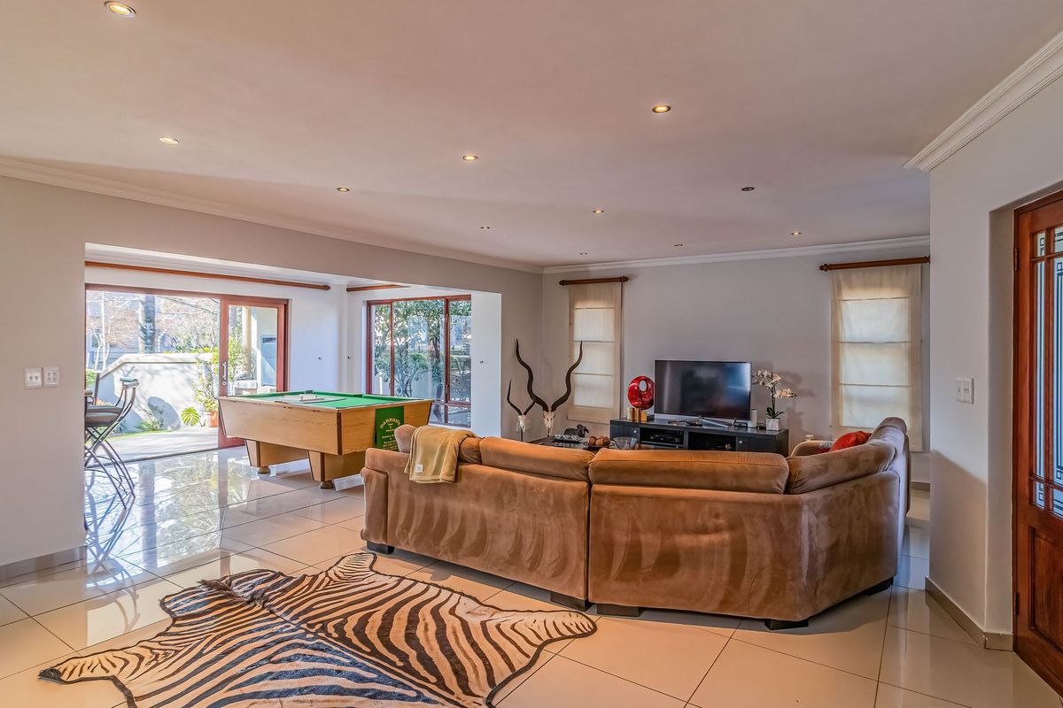Spacious open-plan living area featuring polished tiled floors, recessed downlighting, and large sliding glass doors providing seamless access to the outdoor patio area.