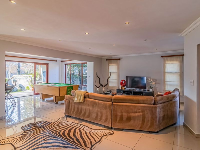 Spacious open-plan living area featuring polished tiled floors, recessed downlighting, and large sliding glass doors providing seamless access to the outdoor patio area.