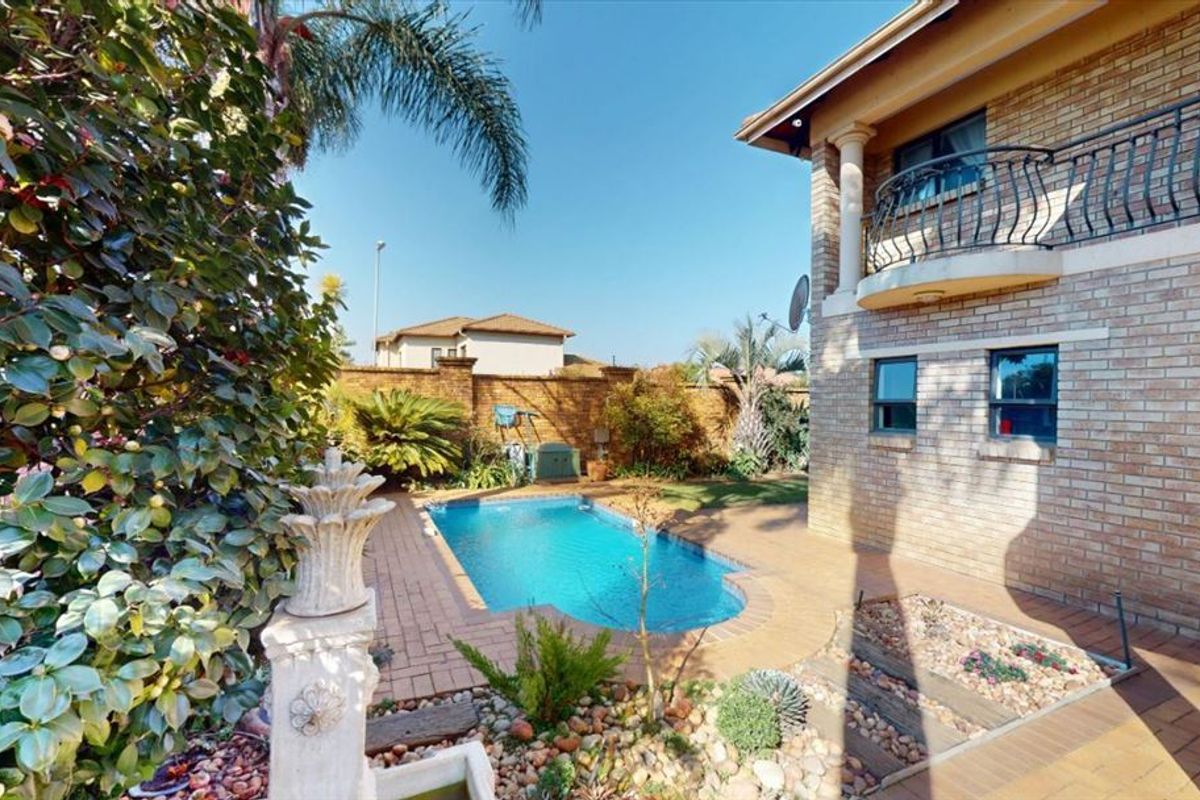 Outdoor pool area featuring a swimming pool, brick paving, and a brick boundary wall, adjacent to the townhouse facade with a balcony.