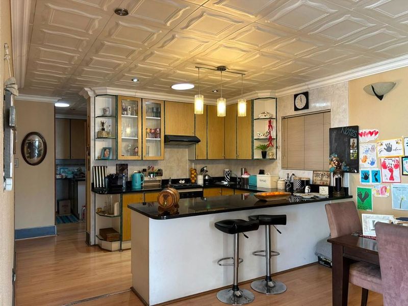 A functional kitchen featuring granite countertops, a breakfast bar, and built-in cabinetry, with a distinct coffered ceiling and laminate flooring throughout.