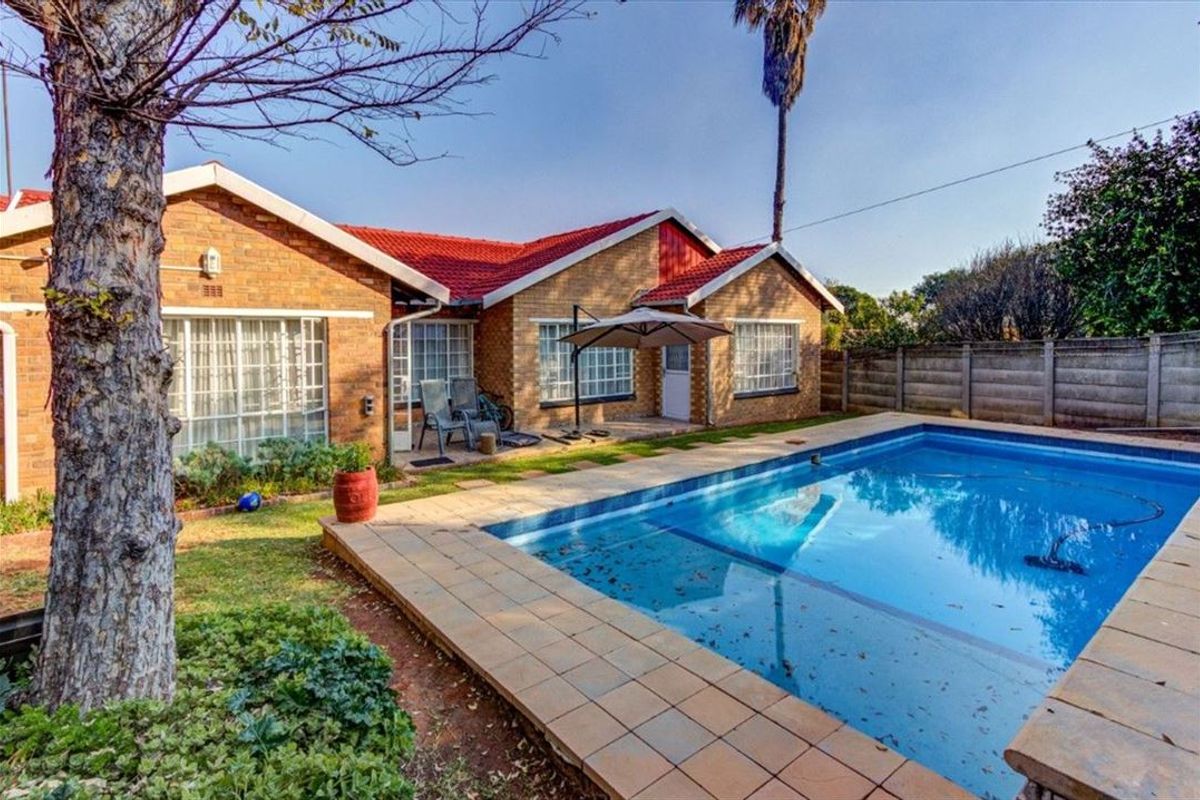 Rear view of the house featuring a swimming pool with tiled surround, brick exterior walls, and a red tiled roof.