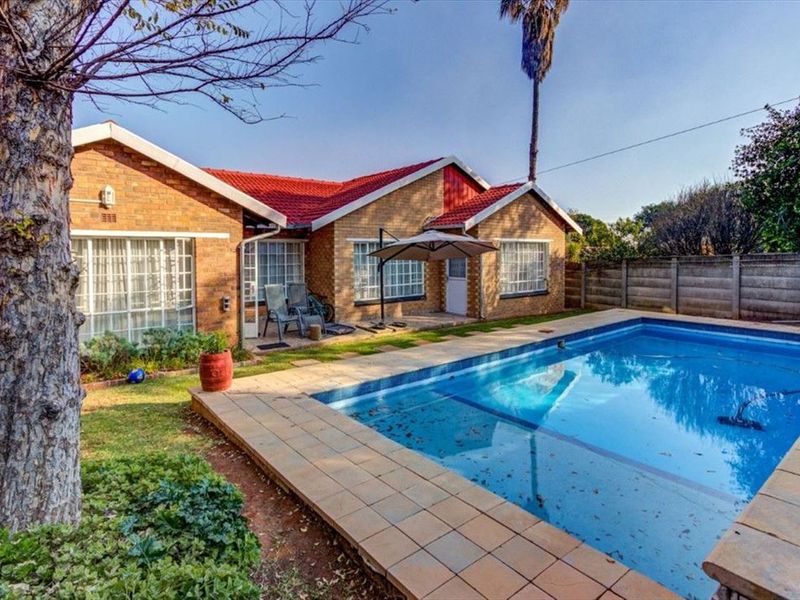 Rear view of the house featuring a swimming pool with tiled surround, brick exterior walls, and a red tiled roof.
