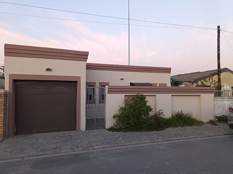 Front elevation of a residential property featuring a single garage, secure pedestrian gate, and a paved driveway with boundary walling.