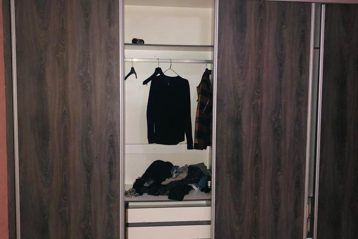 A bedroom featuring a large, dark wood-grain built-in sliding door wardrobe with integrated shelving and drawer storage.