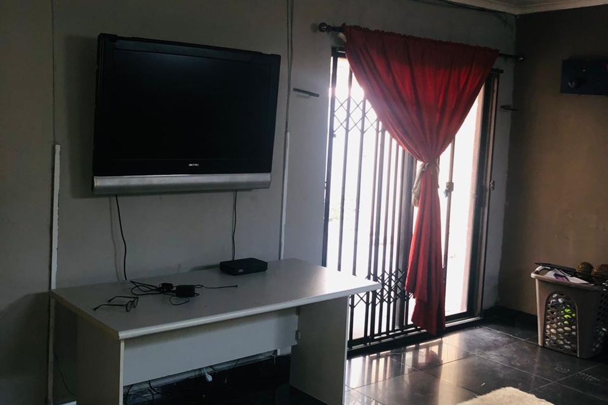 Living room area featuring dark tiled flooring and a sliding door with security gate access to the exterior.