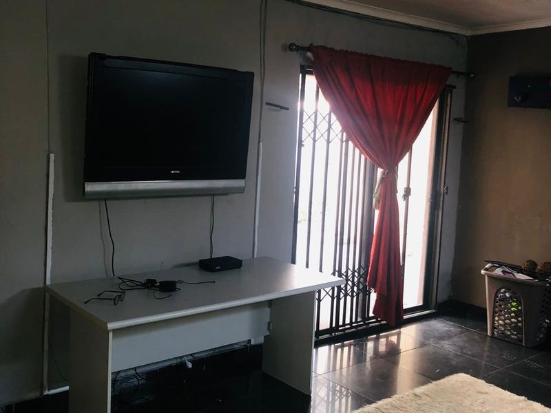 Living room area featuring dark tiled flooring and a sliding door with security gate access to the exterior.
