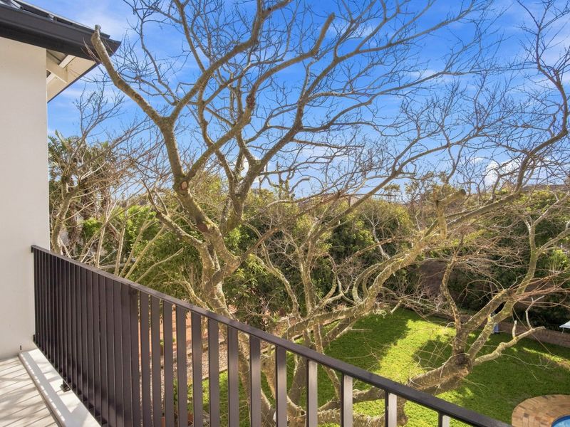 A private balcony featuring a modern metal balustrade, offering an elevated view over the lush garden and surrounding greenery.