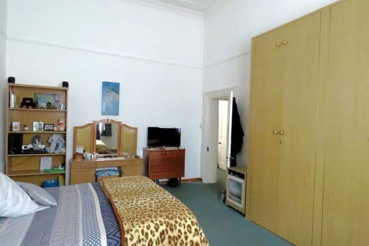 Spacious bedroom featuring high ceilings with coved detailing, a large built-in wardrobe, and a classic picture rail.