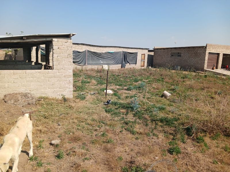 Rear view of the farm property showing multiple outbuildings constructed from cinder blocks with corrugated roofing and an open yard area.