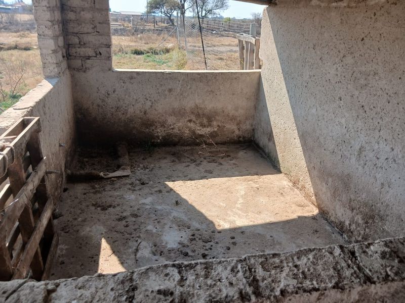A basic, unfinished utility or farm storage space featuring exposed brick and concrete construction, suitable for renovation or repurposing.