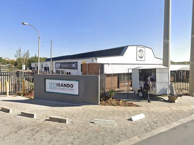 Front entrance view of Isando Business Park featuring paved driveway, security fencing, and prominent business signage.
