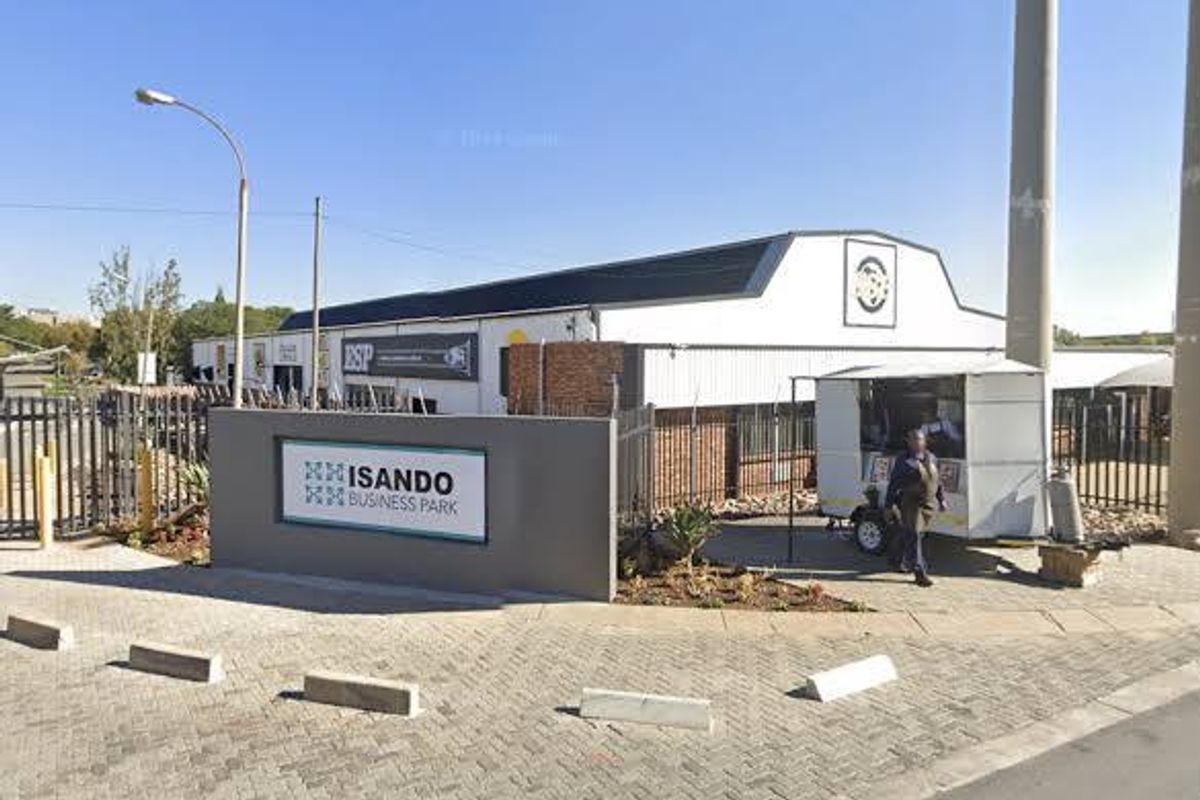 Front entrance view of Isando Business Park featuring paved driveway, security fencing, and prominent business signage.