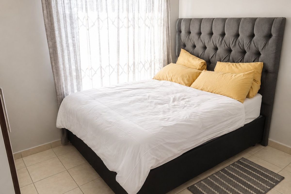 A well-lit bedroom featuring neutral tiled flooring and a security gate installed over the window.