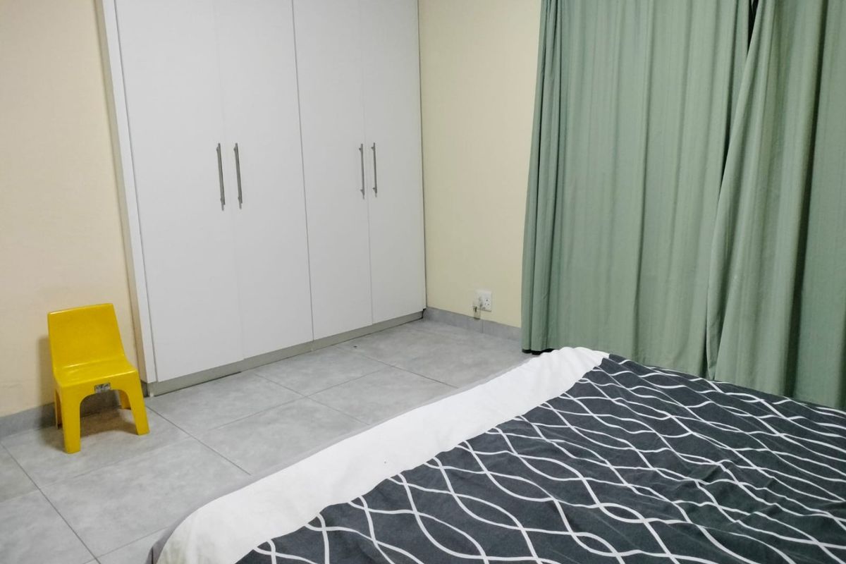 A bedroom featuring neutral tiled flooring and white built-in cupboards, providing functional storage space.