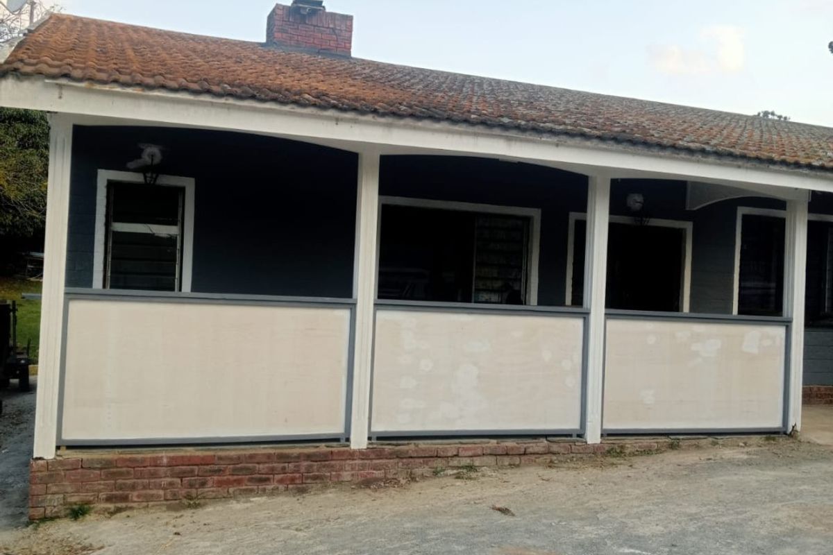Rear view of the property featuring a covered patio area with a brick base and terracotta tiled roof.