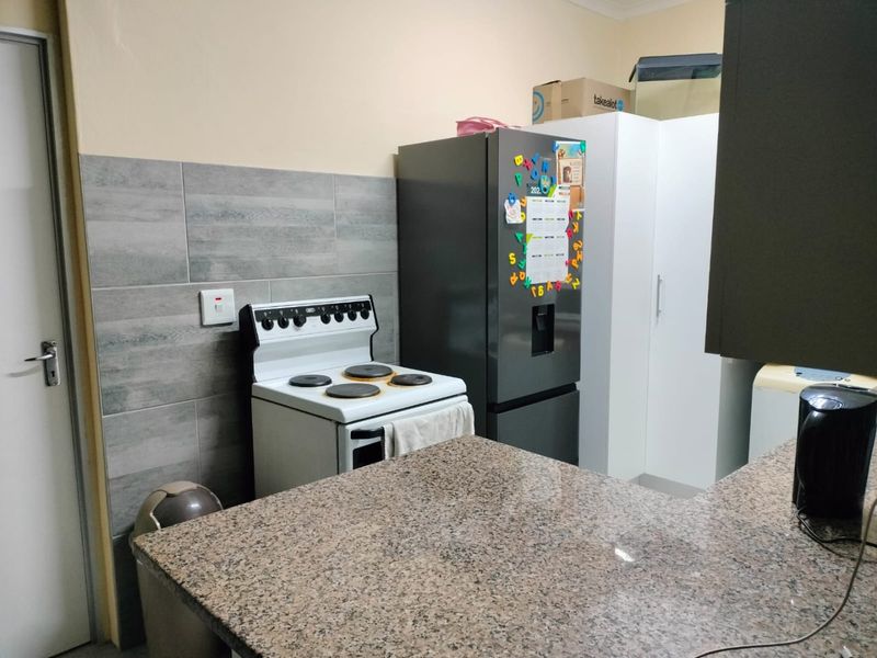 A functional kitchen area featuring granite countertops, a tiled backsplash, and a freestanding stove with built-in cabinetry.