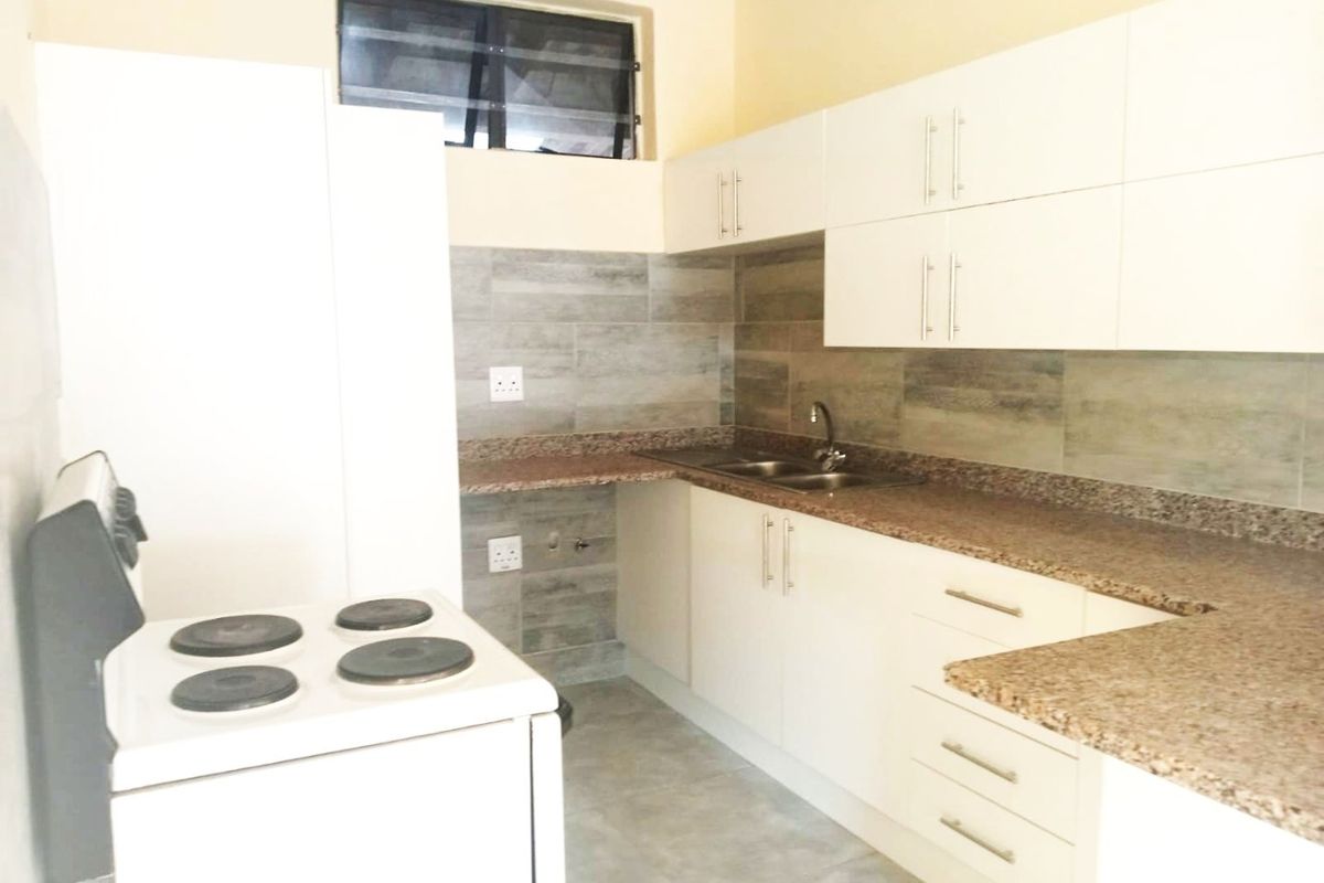 A clean, functional kitchen featuring white cabinetry, granite countertops, a tiled backsplash, and a freestanding electric stove.