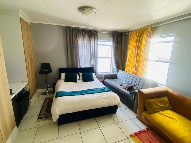 A functional bedroom featuring tiled flooring, a built-in wardrobe, and natural light from dual windows.