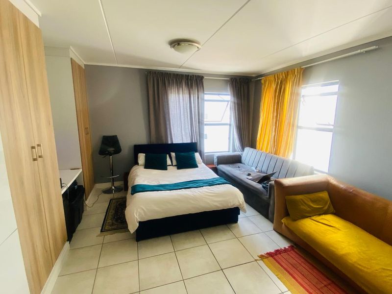 A functional bedroom featuring tiled flooring, built-in cupboards, and natural light from dual windows, offering a versatile space for rest and relaxation.