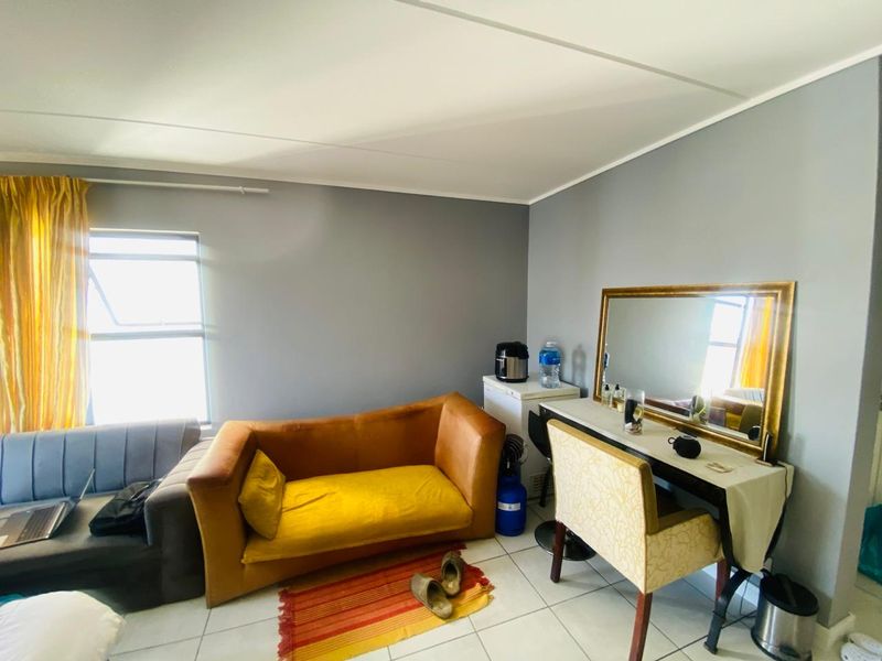 A bedroom featuring tiled flooring and a casement window, currently utilized as a multi-purpose living and dressing space.