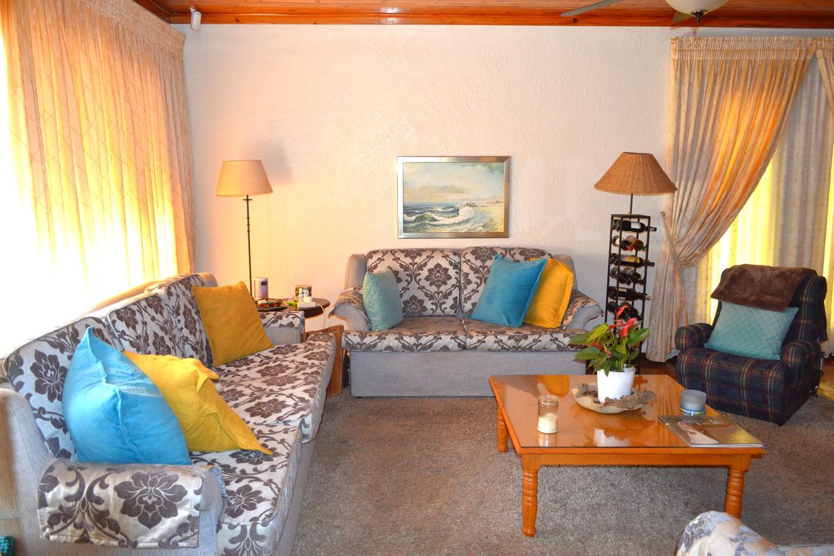 A comfortable living room featuring carpeted flooring and timber ceiling trim, providing a traditional and lived-in atmosphere.