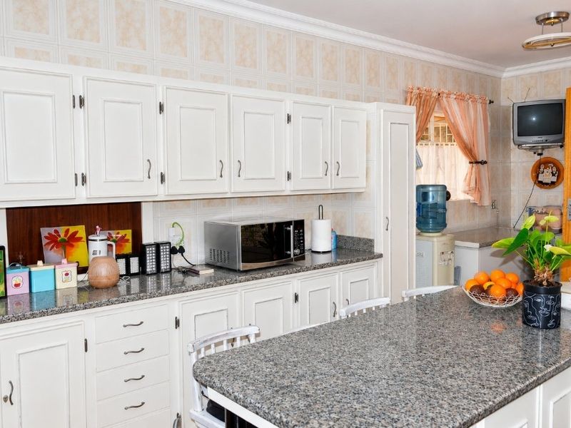 A functional kitchen featuring granite countertops, ample built-in cabinetry, and a central island, offering a practical layout with potential for modern updates.