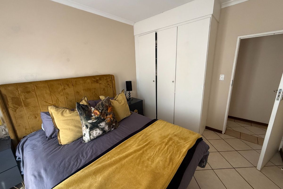 A bedroom featuring tiled flooring, a built-in wardrobe, and neutral wall finishes.