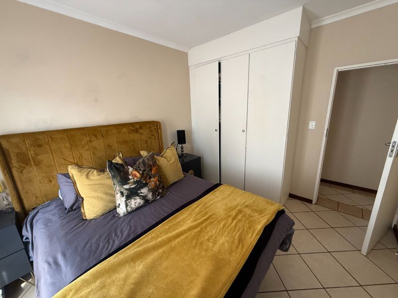 A bedroom featuring tiled flooring, a built-in wardrobe, and neutral wall finishes.