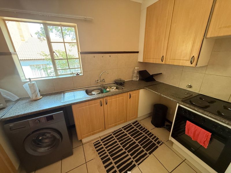 A functional kitchen featuring light wood cabinetry, granite countertops, a stainless steel sink, and a built-in oven with an electric hob.