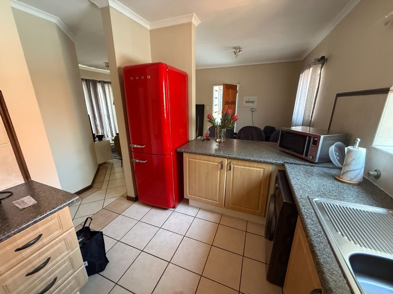 A functional kitchen featuring laminate cabinetry, granite-look countertops, and tiled flooring, providing a practical layout with direct access to the living area.