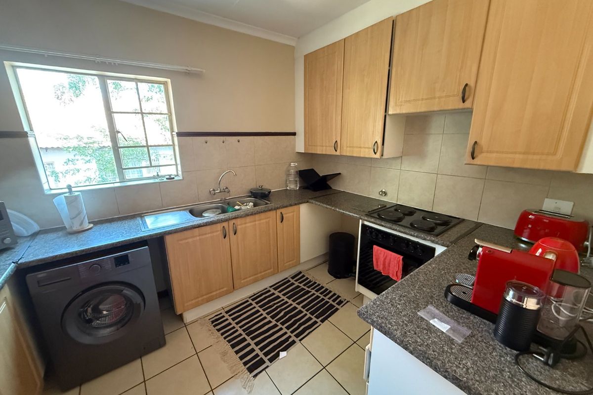 Functional kitchen featuring laminate cabinetry, granite countertops, built-in oven, electric hob, and tiled flooring with a window providing natural light.