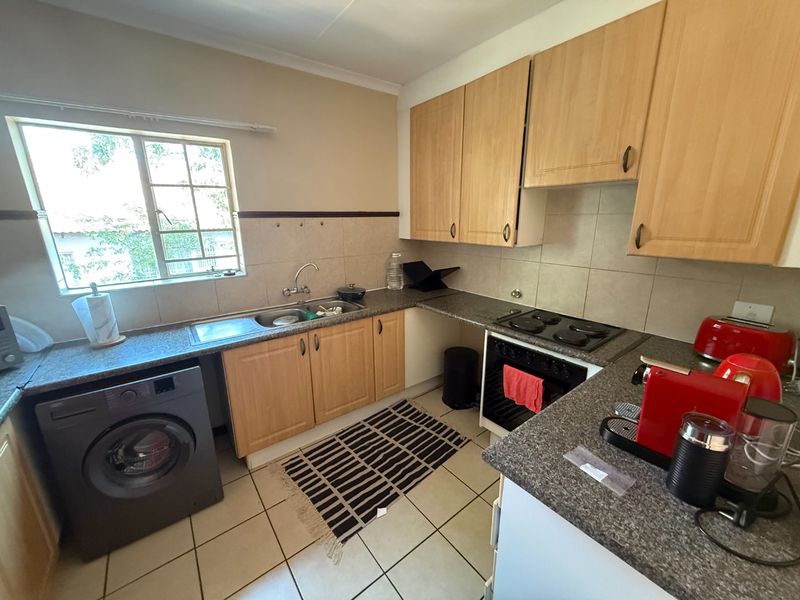 Functional kitchen featuring laminate cabinetry, granite countertops, built-in oven, electric hob, and tiled flooring with a window providing natural light.