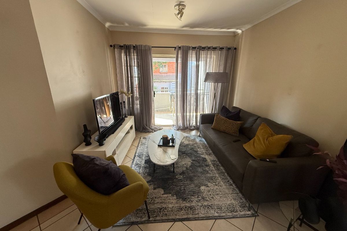 A cozy living room featuring tiled flooring and a sliding glass door that provides access to an outdoor balcony area.