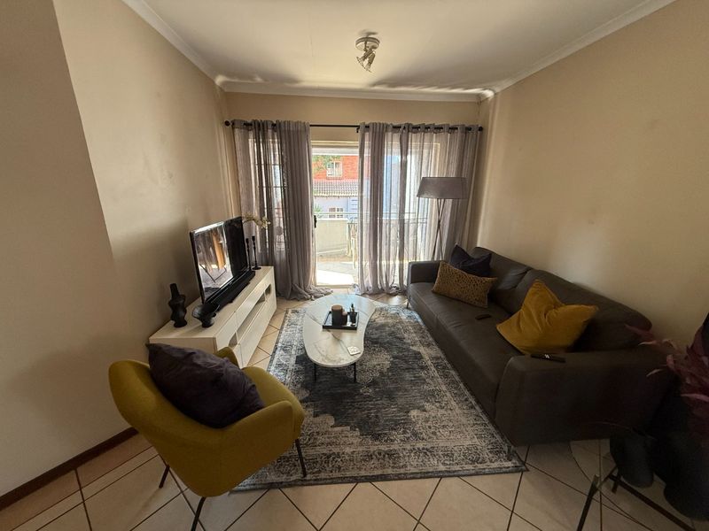 A cozy living room featuring tiled flooring and a sliding glass door that provides access to an outdoor balcony area.
