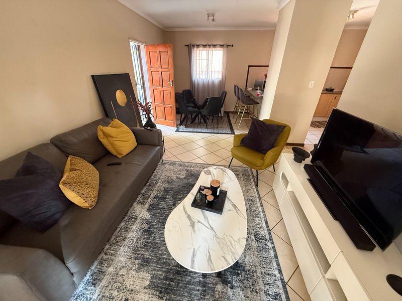 Open-plan living area featuring tiled flooring, connecting to a dining space and kitchen with a breakfast bar.