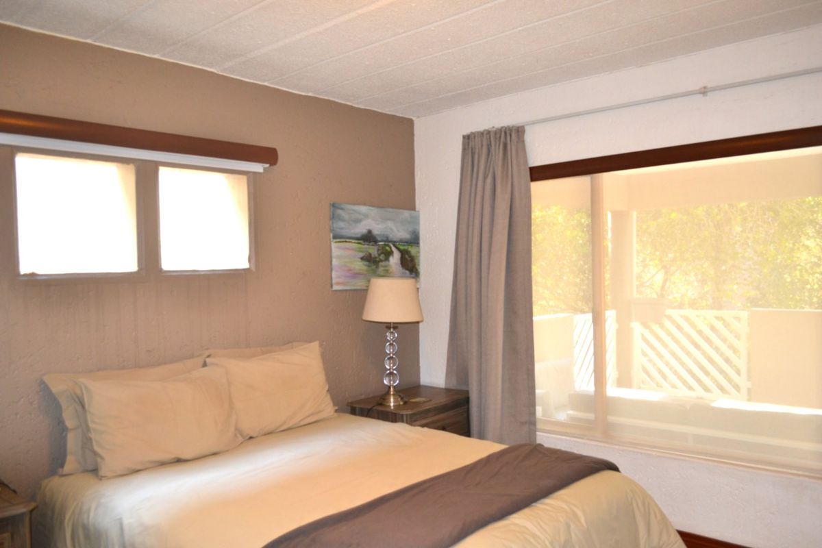 A bedroom featuring textured ceilings, timber window frames, and a sliding glass door providing access to an outdoor area.