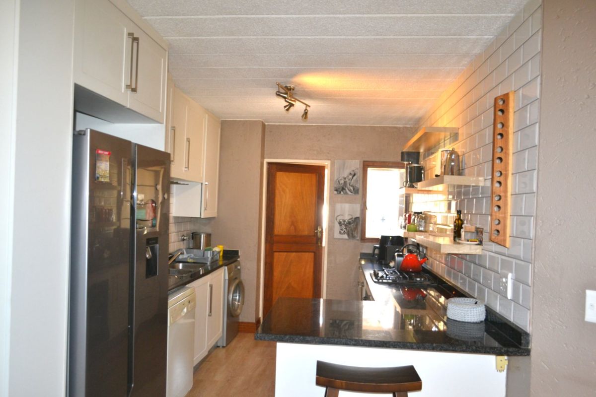A functional kitchen featuring granite countertops, subway tile backsplash, built-in cabinetry, and a gas hob with integrated floating shelving.