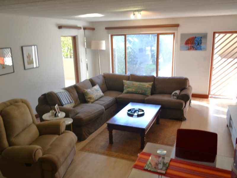 A spacious living room featuring laminate flooring, large sliding glass doors providing natural light, and access to an outdoor area.